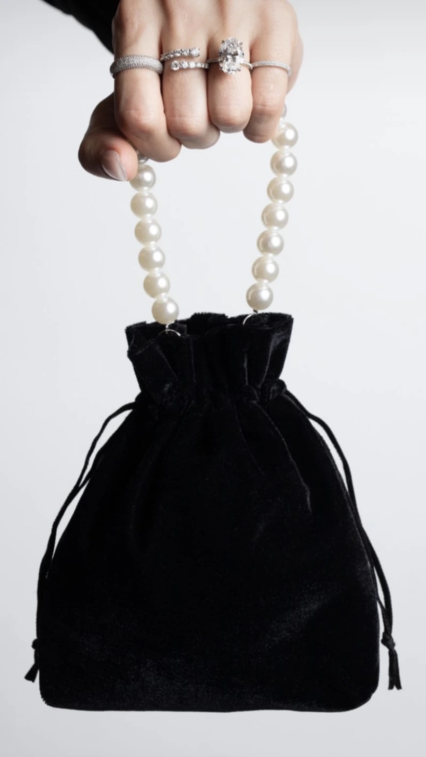 Ring Concierge pearl-handled velvet pouch held by a hand wearing rings